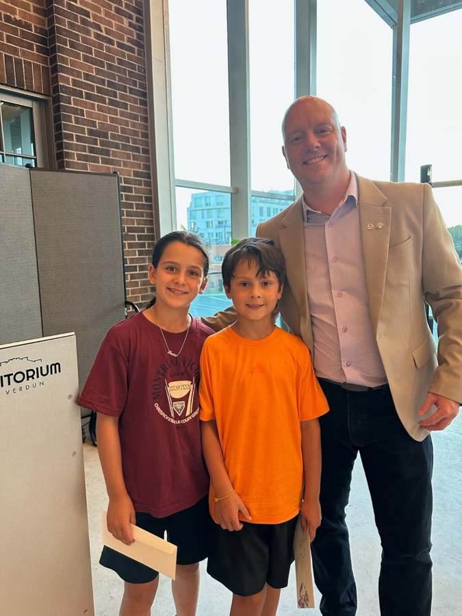 Deux jeunes participants posent avec un représentant lors de l’événement.
