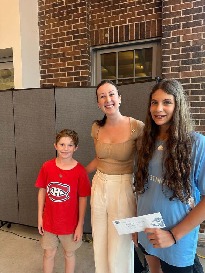 Deux jeunes participants et une représentante lors d’une remise de reconnaissance.