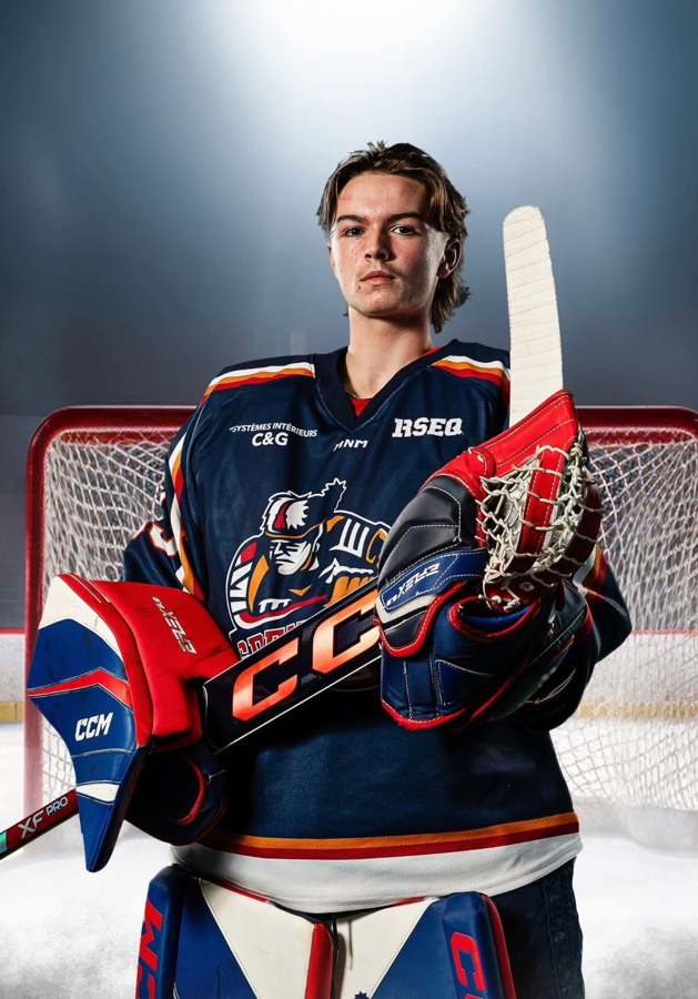 Portrait d’un jeune gardien de hockey en équipement devant son filet.