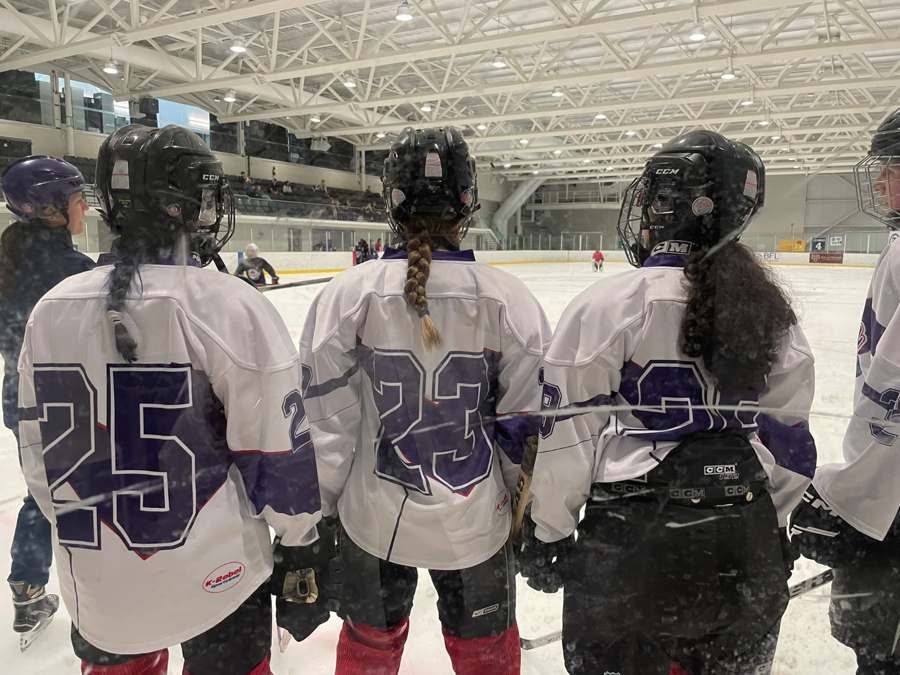 Jeunes joueuses de hockey AHMV vues près des bandes de la patinoire.