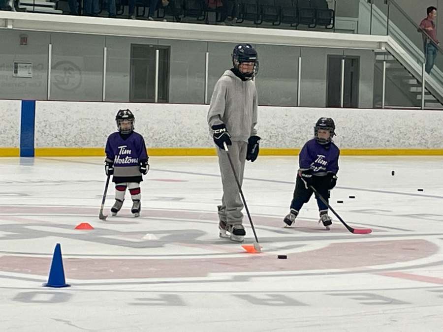 Jeunes joueurs AHMV réalisant un exercice avec cônes sur la glace.